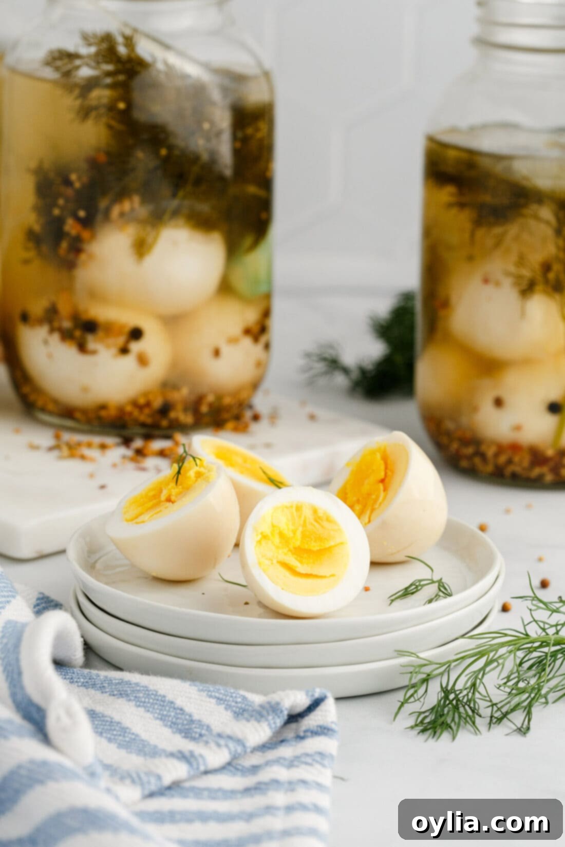 Two Pickled Eggs cut in half on a plate with jars of Pickled Eggs in the background, showcasing their vibrant color and texture.