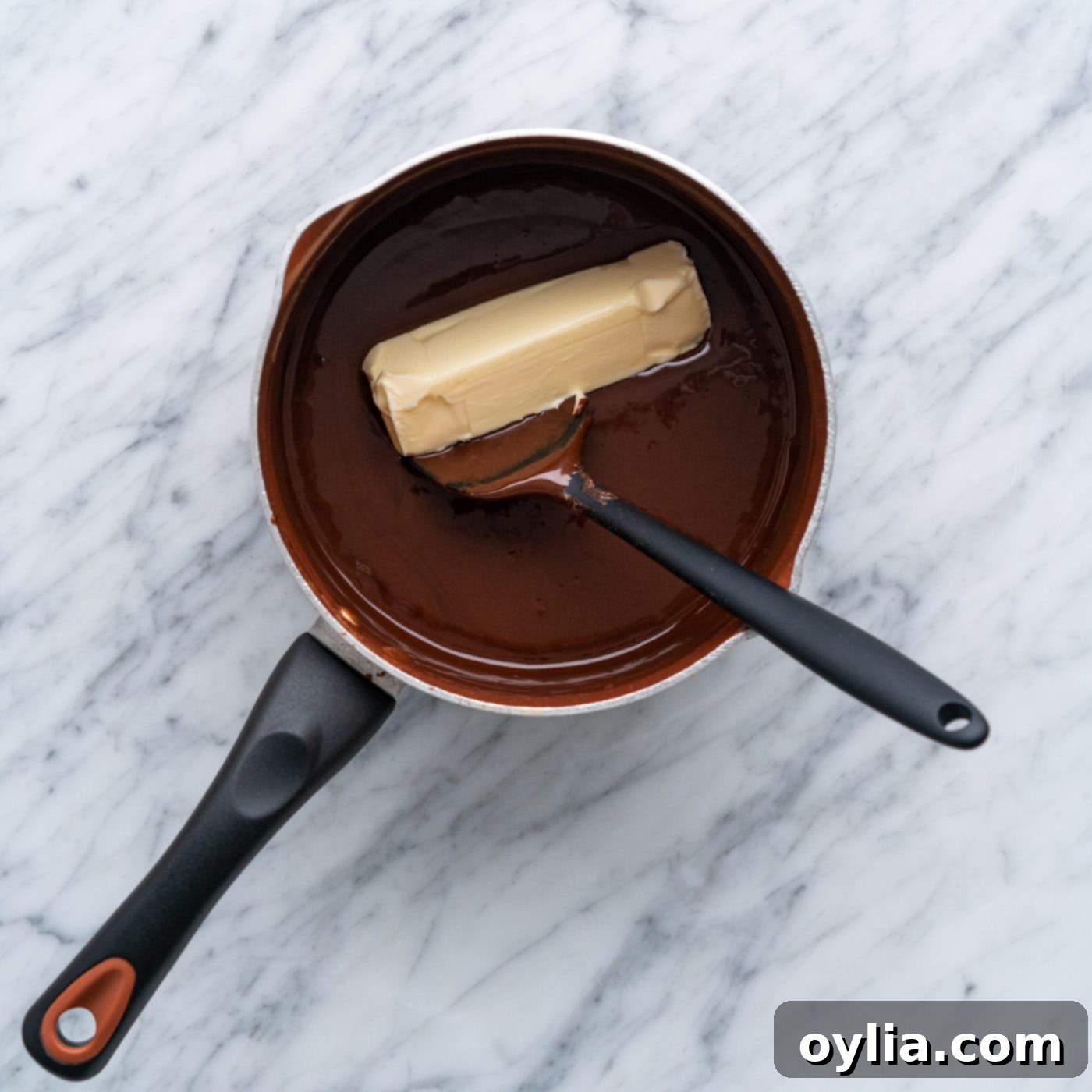 adding butter to hot fudge in a pot