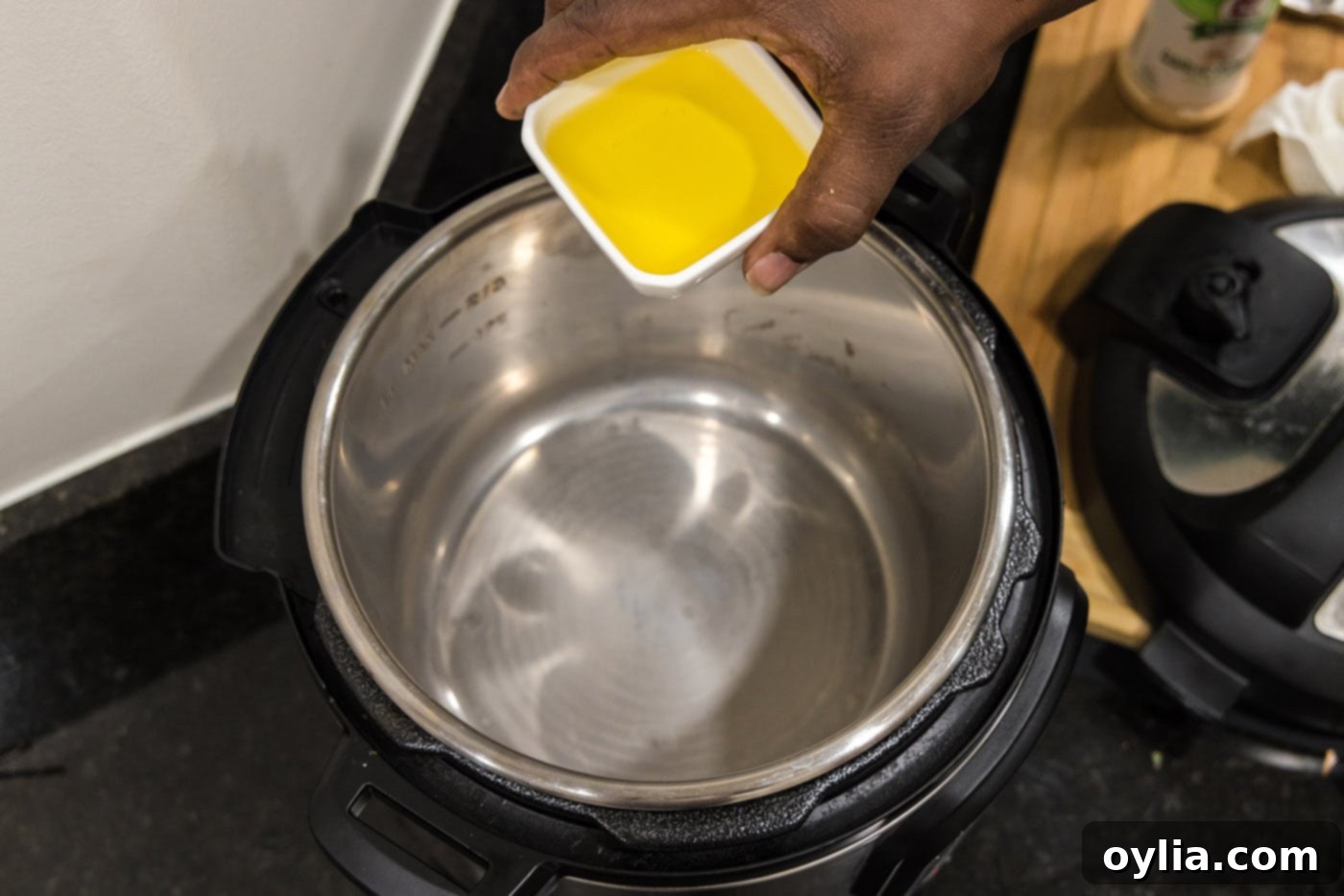 Adding olive oil to the bottom of the Instant Pot, preparing for searing.