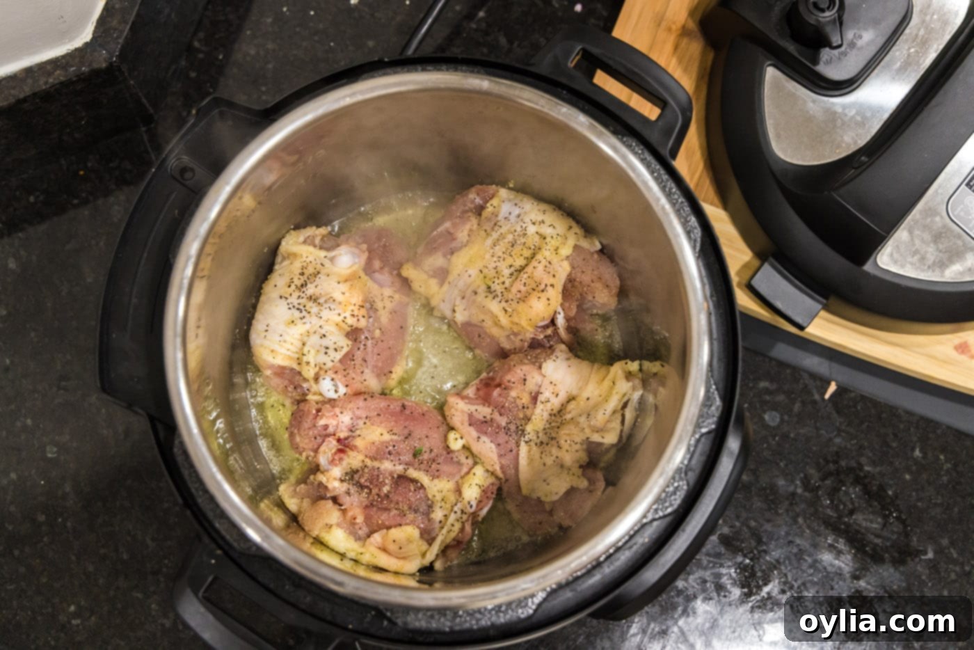 Searing chicken thighs in the Instant Pot on sauté mode to achieve crispy skin.