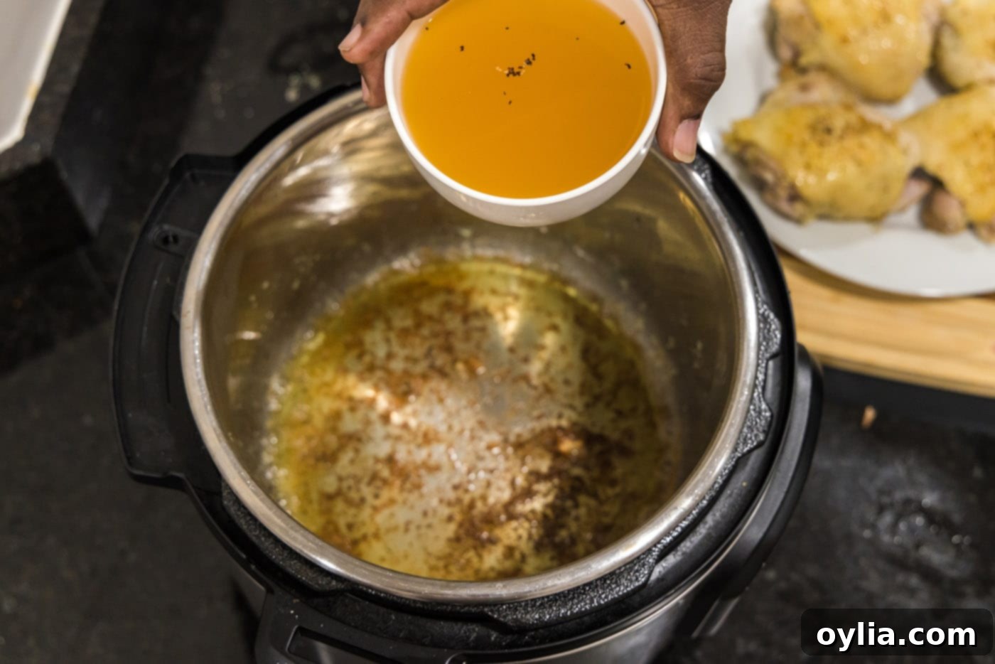 Deglazing the Instant Pot by adding chicken stock and scraping up browned bits for flavor.