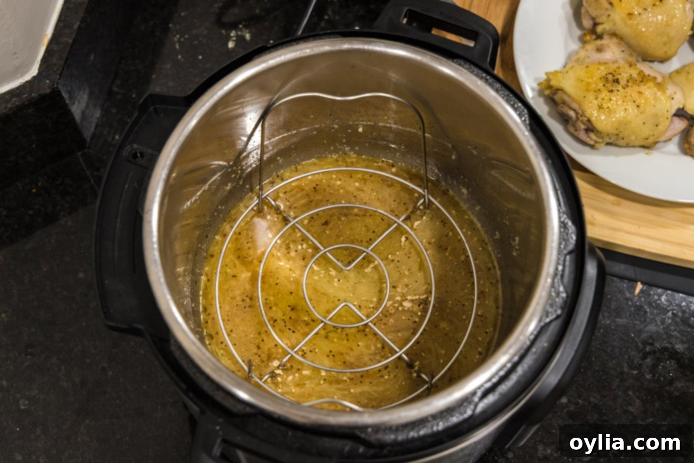 Placing the trivet inside the Instant Pot before adding the chicken thighs.