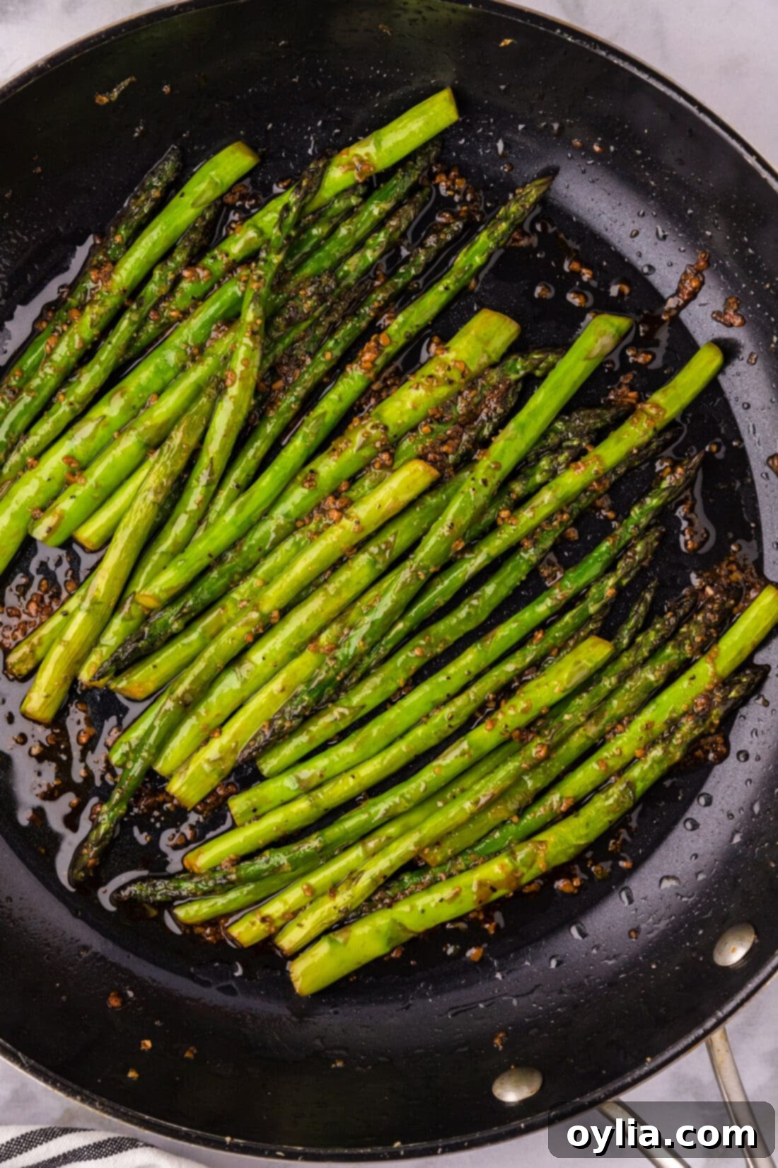 Close up photo of Sautéed Asparagus in a skillet, glistening with soy garlic sauce