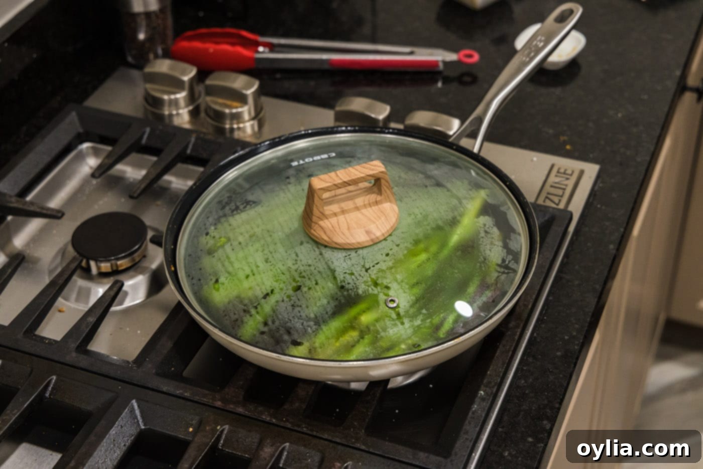 A skillet with freshly sauteed asparagus, covered with a lid to keep warm before serving.