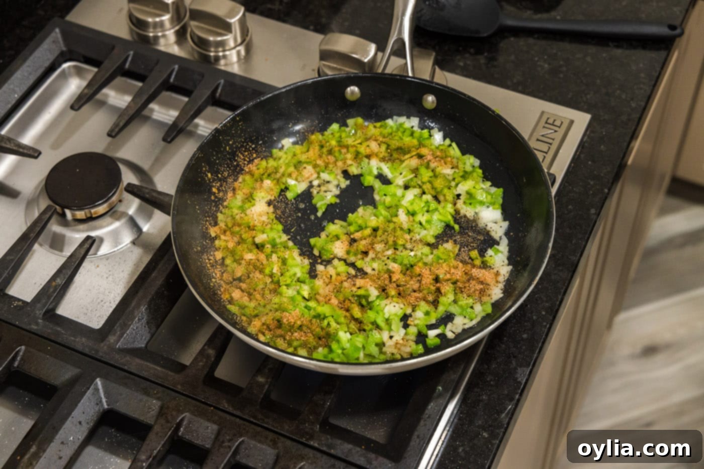 cajun seasoning on top of bell pepper, onion, and celery in a skillet