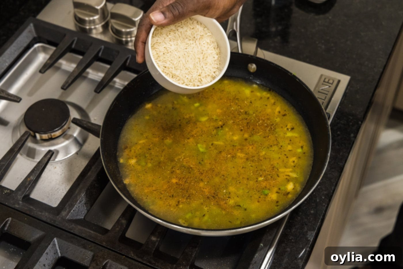 pouring Basmati rice into skillet with chicken stock and vegetables