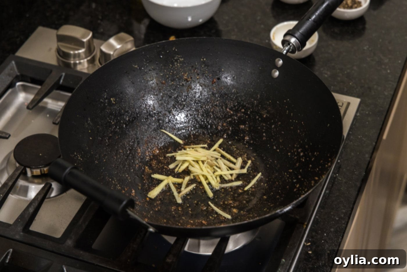Slivered ginger sizzling in a wok with oil.