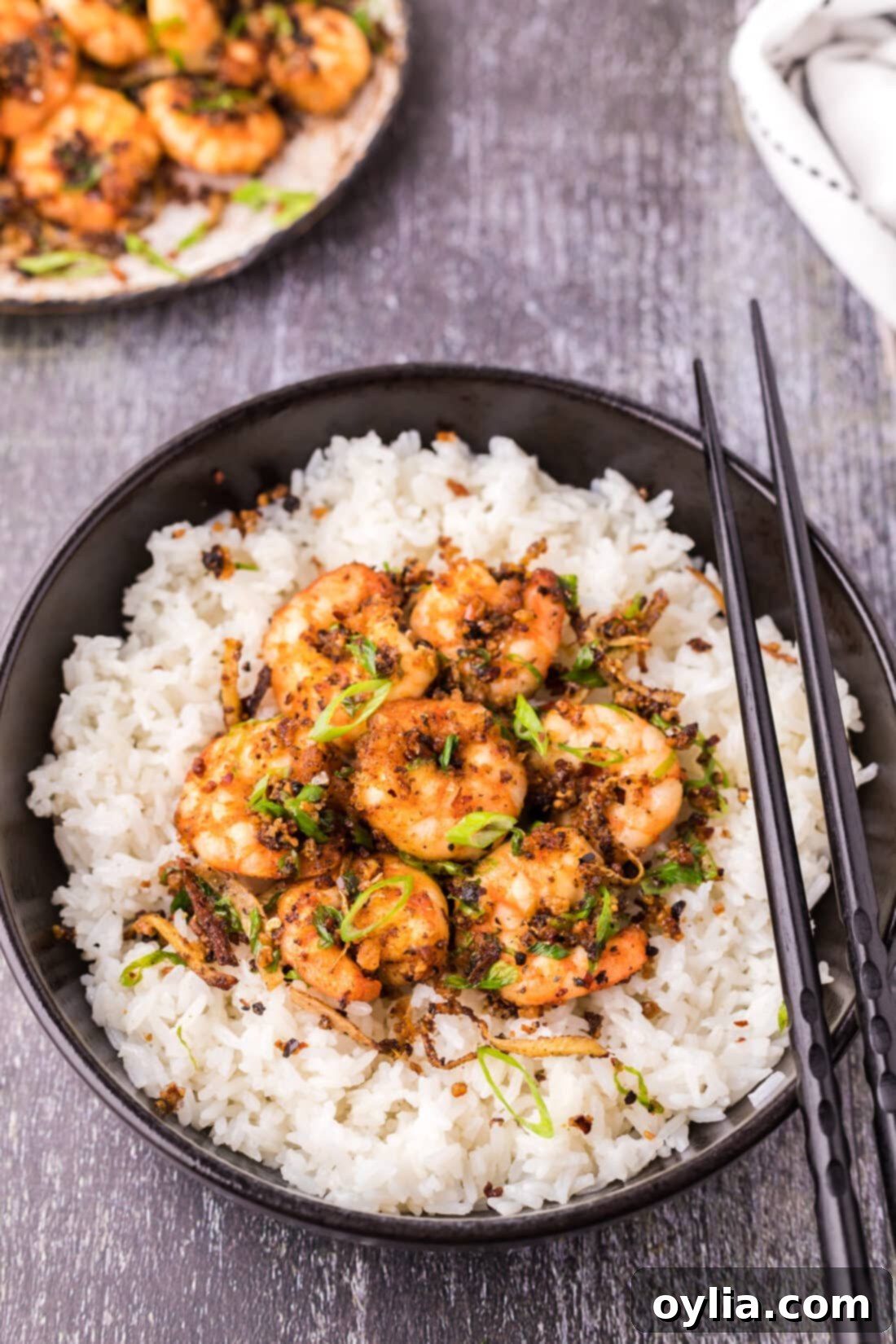 Salt and Pepper Shrimp in a bowl served over rice, garnished with green onions.