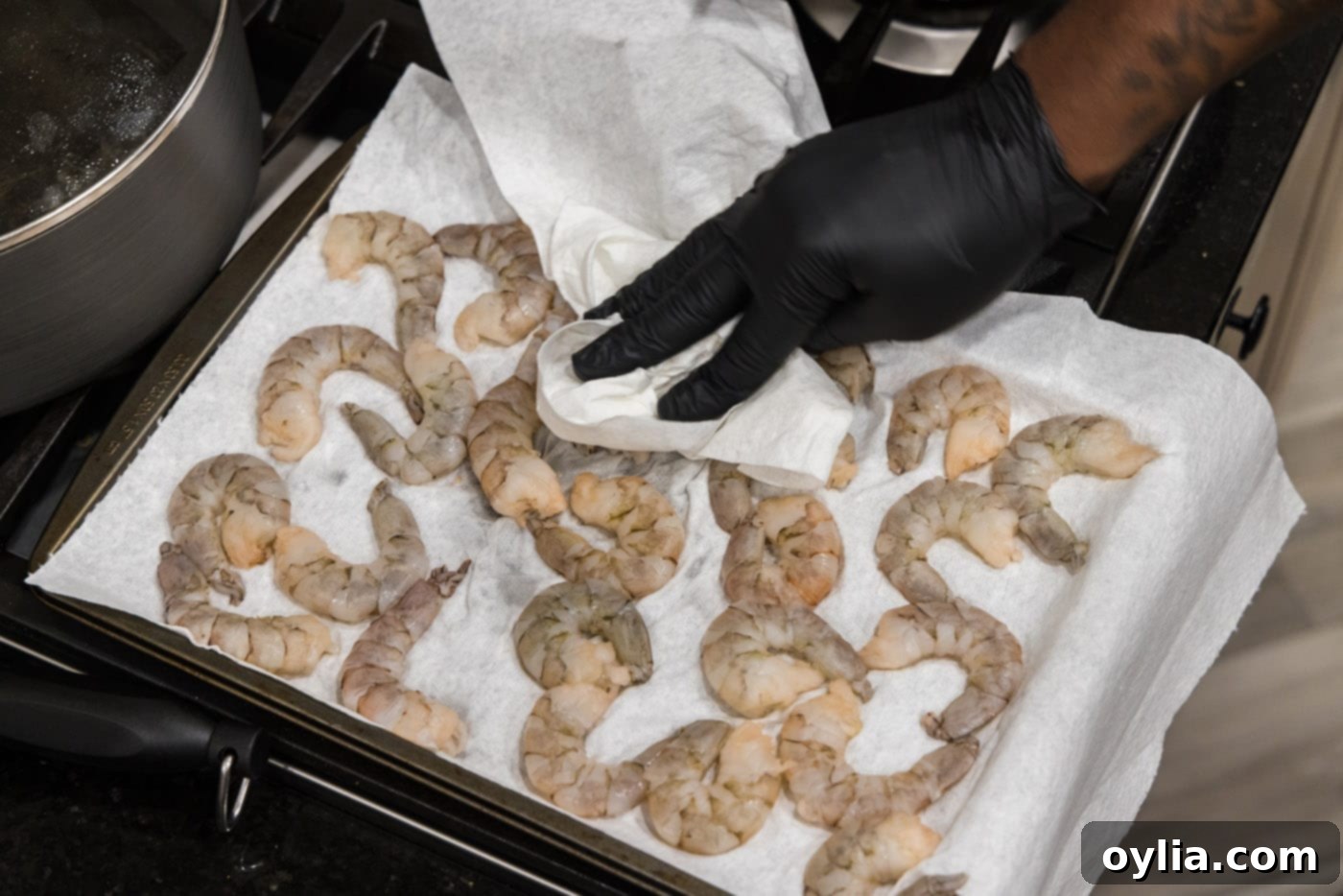 Chef patting shrimp dry with a paper towel, ensuring a crispy coating.