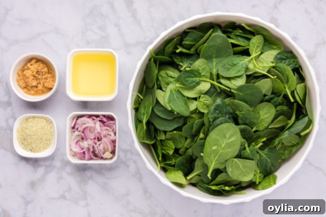 Garlicky Sautéed Spinach 4 Ingredients for Sautéed Spinach laid out on a cutting board: spinach, shallots, garlic, olive oil, and garlic salt.