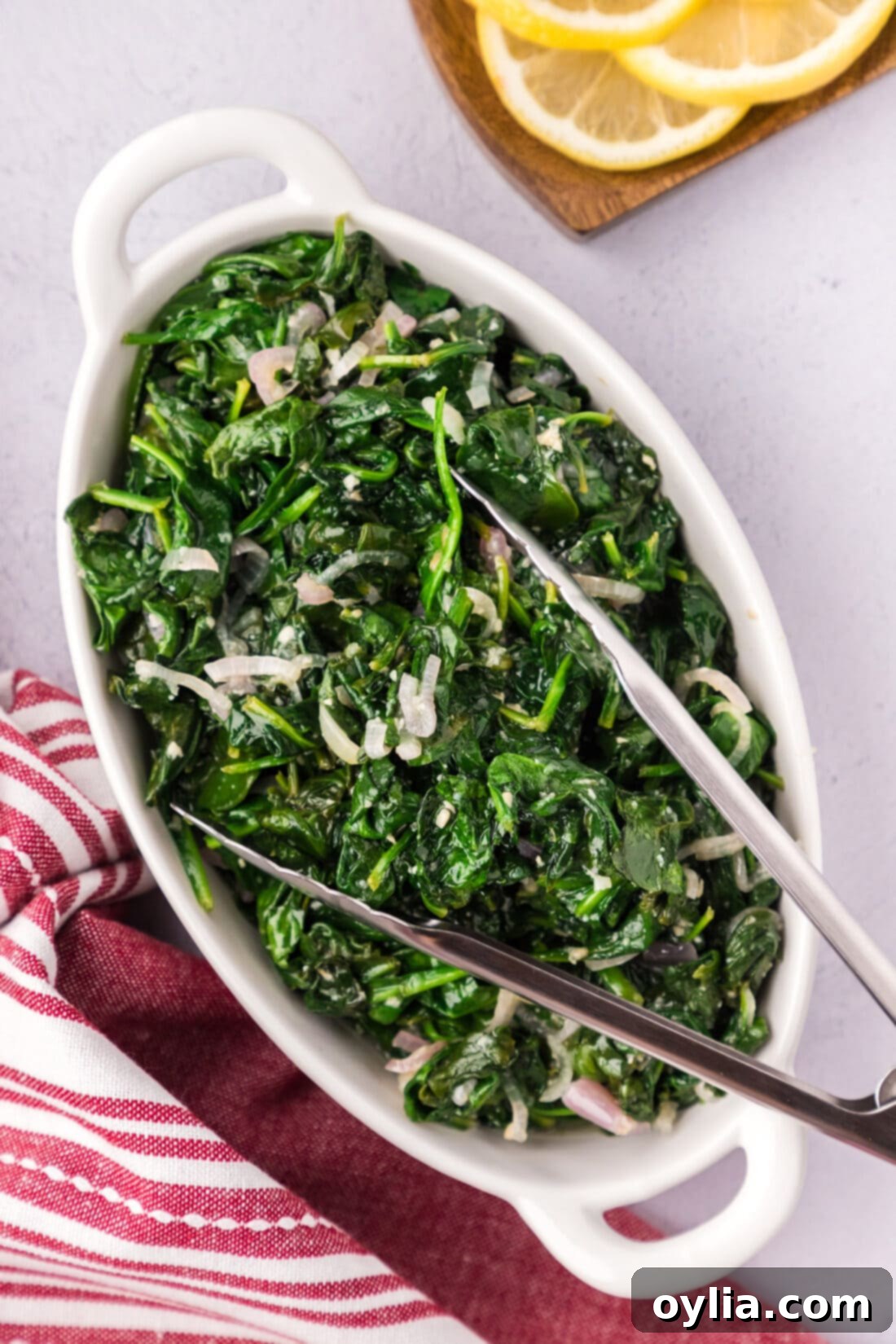 Garlicky Sautéed Spinach 9 Sautéed Spinach in a serving platter with serving tongs, ready to be enjoyed.