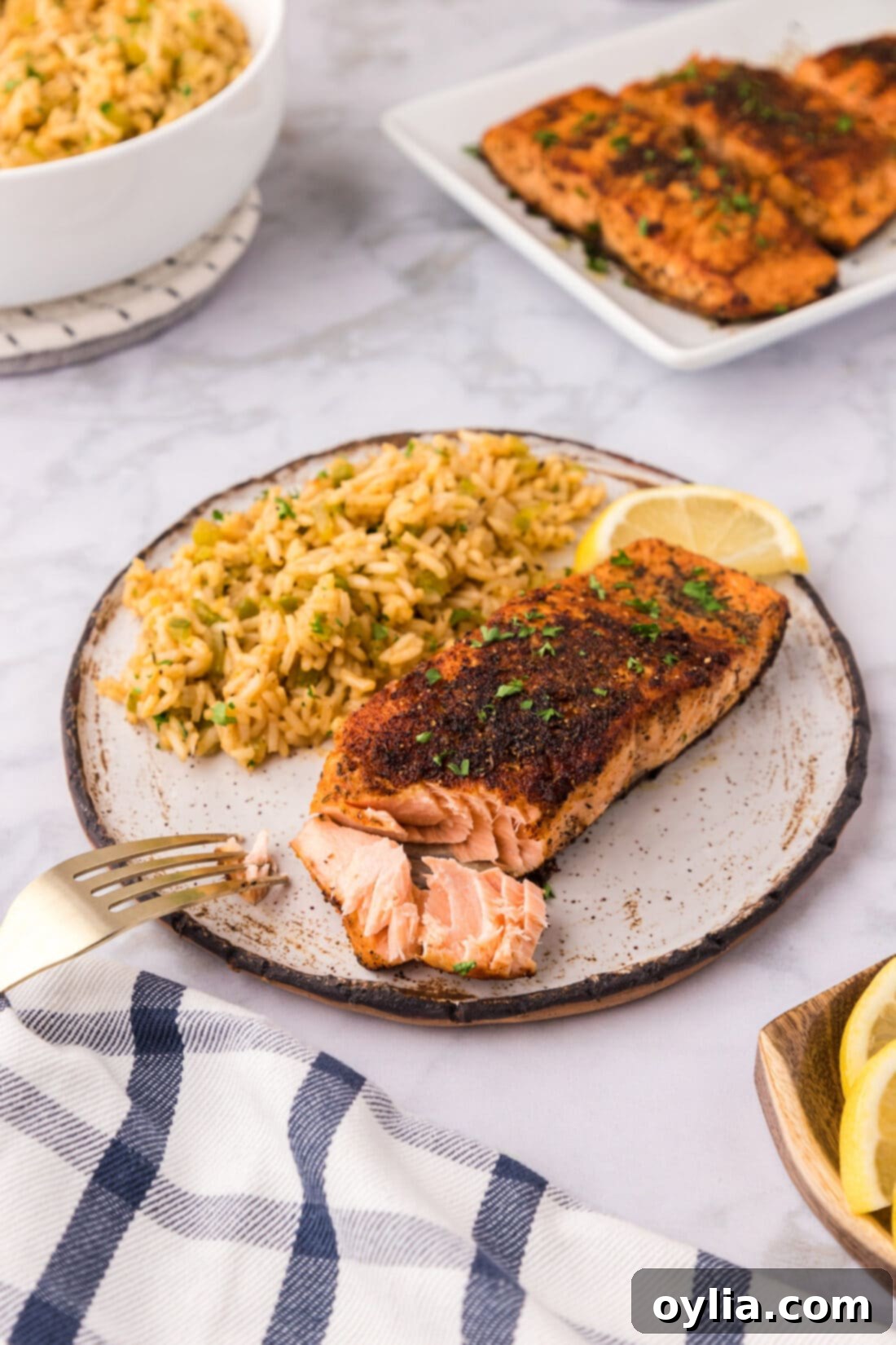 Cajun Salmon on a plate with cajun rice and a lemon slice, garnished with fresh herbs