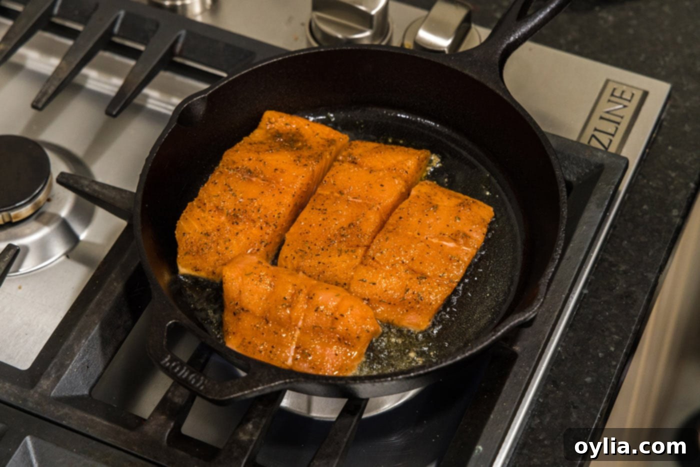 Seasoned salmon fillets placed skin-side down in a hot skillet