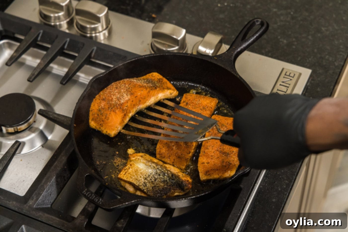 Fish turner gently flipping a salmon fillet in a skillet