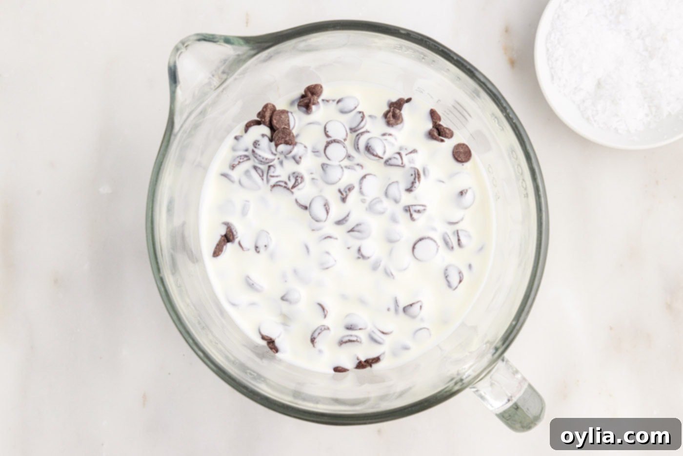 Semi-sweet chocolate chips and heavy cream in a microwave-safe bowl, ready to be heated for ganache.