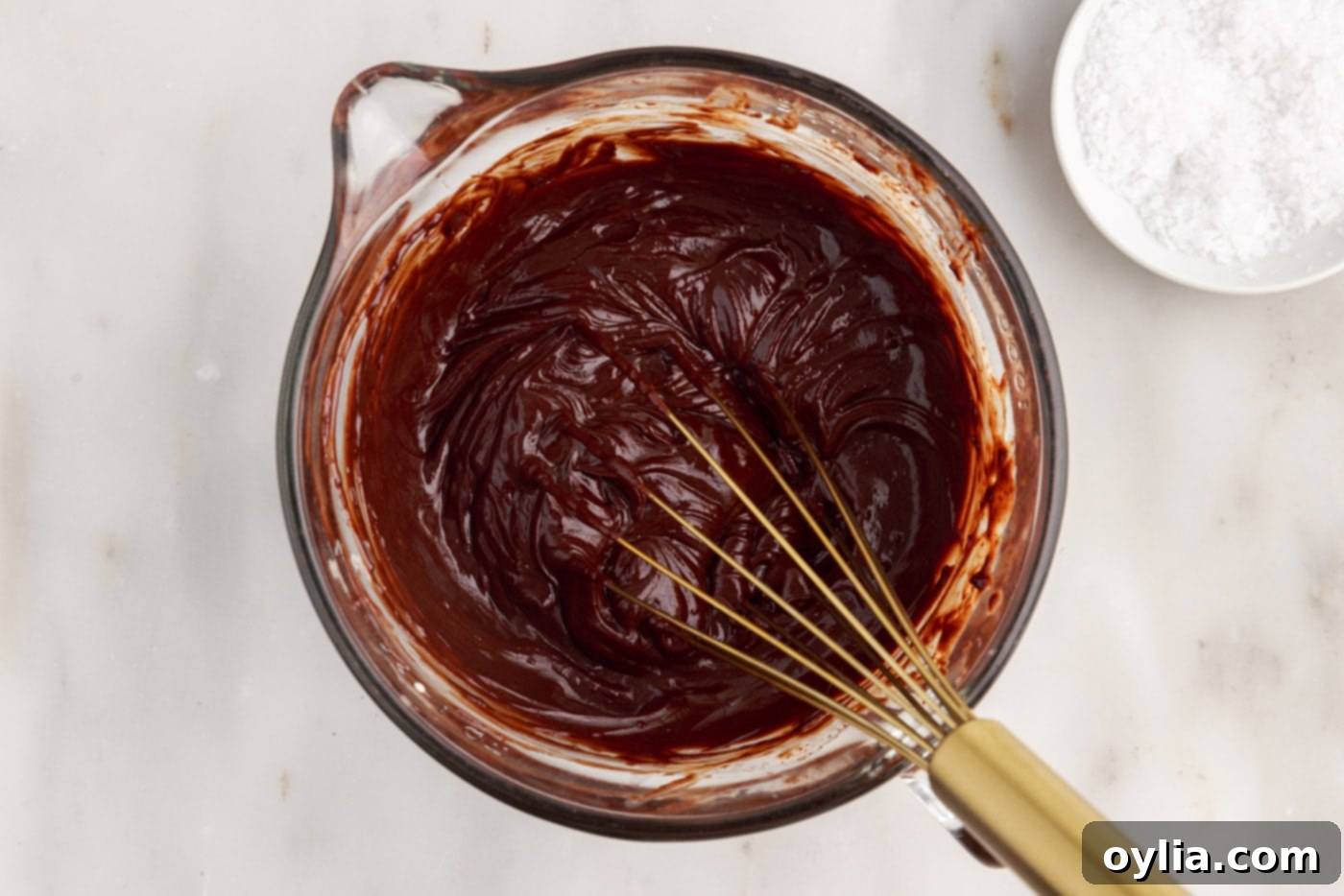 Whisking chocolate ganache in a bowl until it is smooth and shiny.