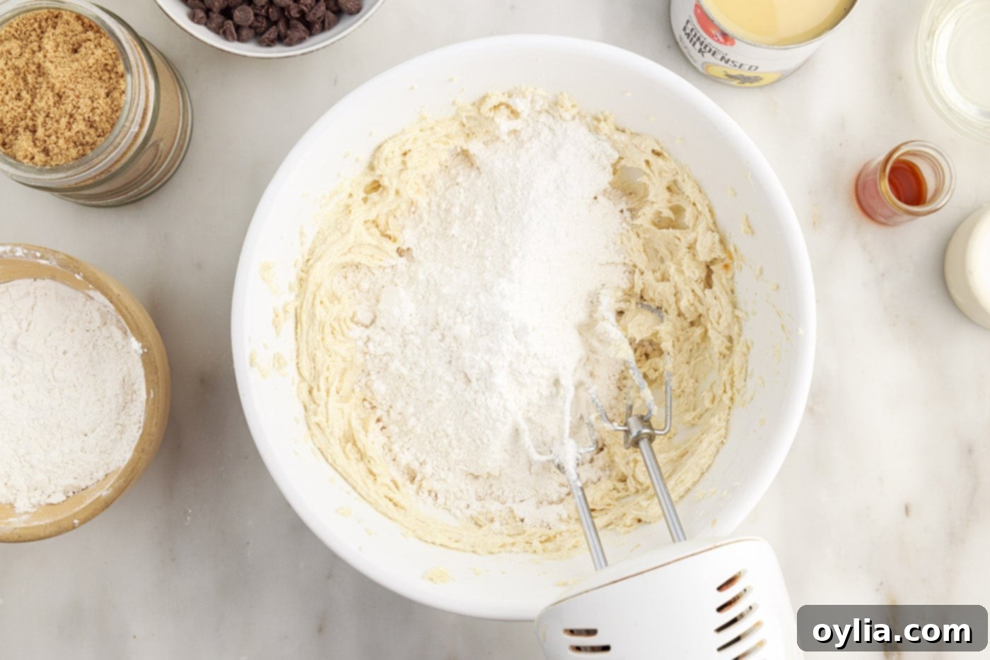 Adding cake flour and salt to the shortbread dough in a mixing bowl.