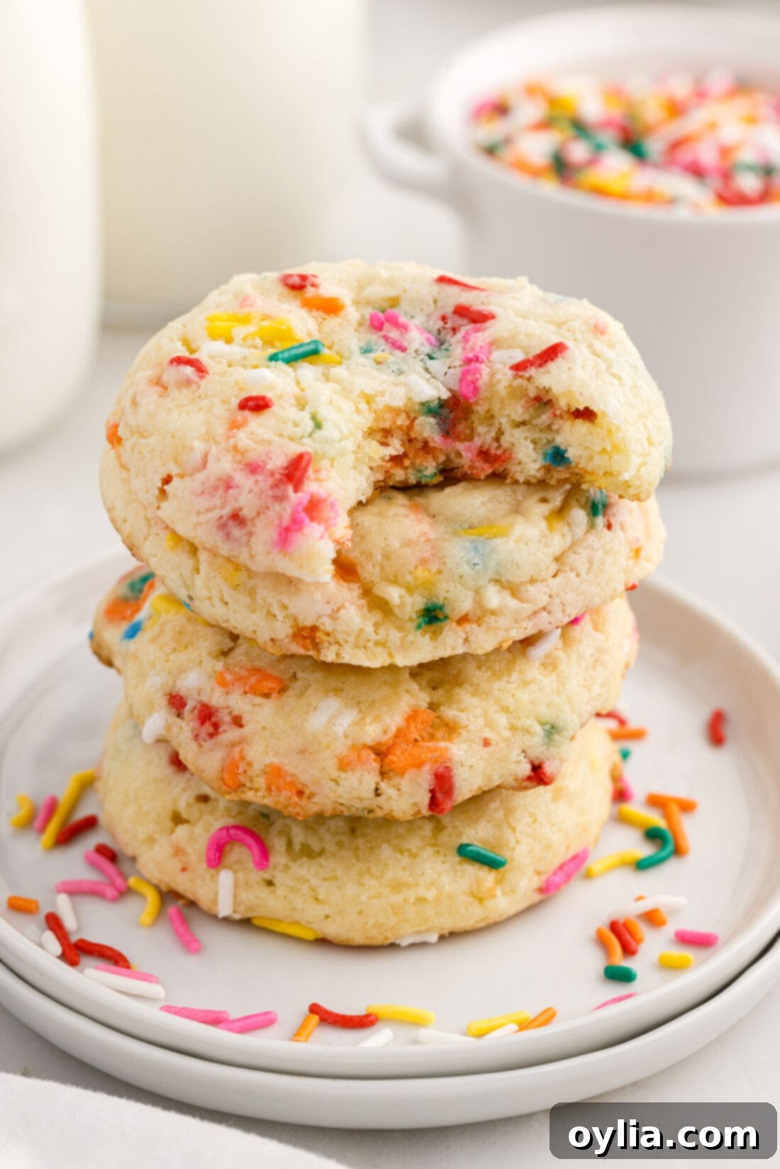 Confetti Cake Cookie Bliss 2 Stack of Funfetti Cake Mix Cookies with a bite taken out of the top one, showcasing the chewy texture and colorful sprinkles.