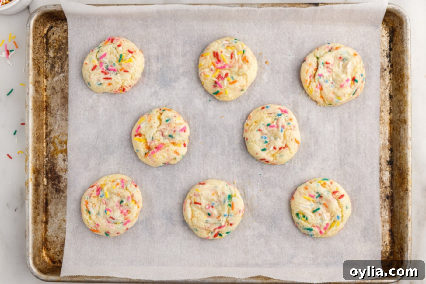 Freshly baked funfetti cookies cooling on a baking sheet, golden and perfectly puffed with visible sprinkles.