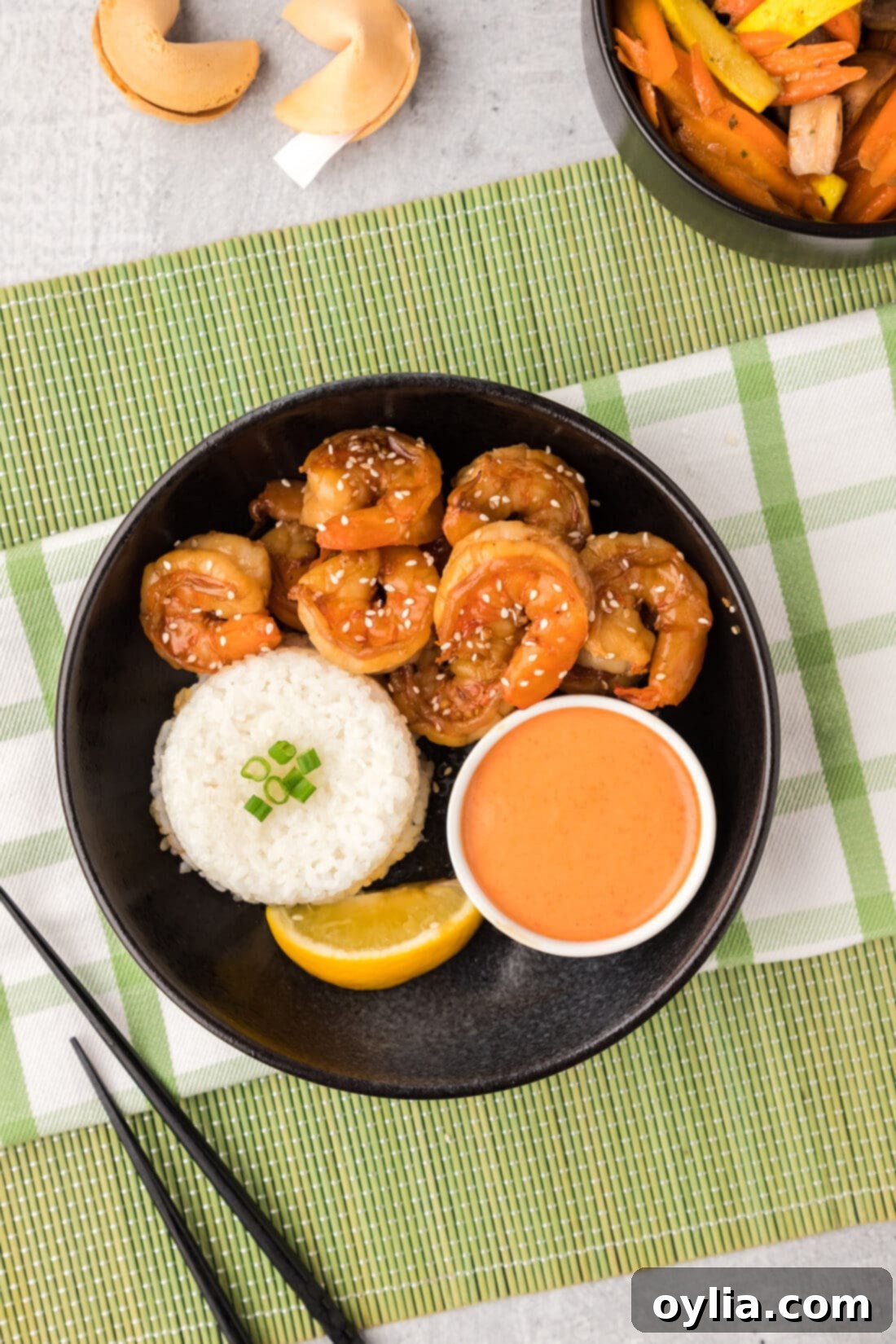 An overhead view of a delicious bowl of Hibachi Shrimp with a side of white rice and a small dish of creamy Yum Yum Sauce, garnished with sesame seeds.