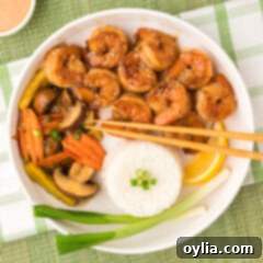 A vibrant bowl of Hibachi Shrimp served with assorted stir-fried vegetables and fluffy white rice, ready to be enjoyed.