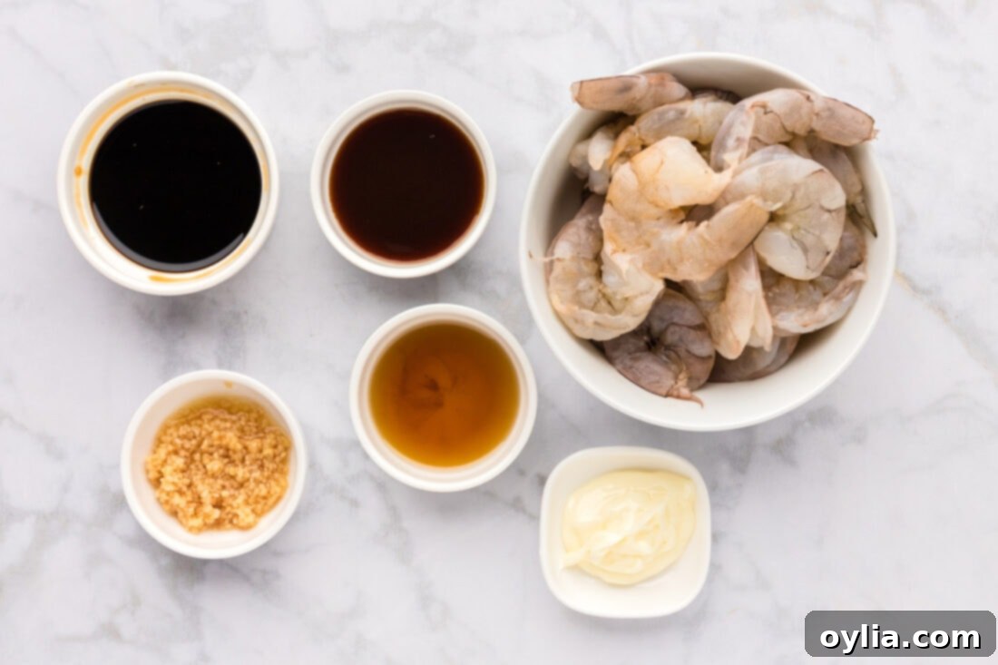 A flat lay photo displaying all the fresh ingredients needed for making delicious hibachi shrimp: raw shrimp, butter, garlic, sesame oil, oyster sauce, and soy sauce.