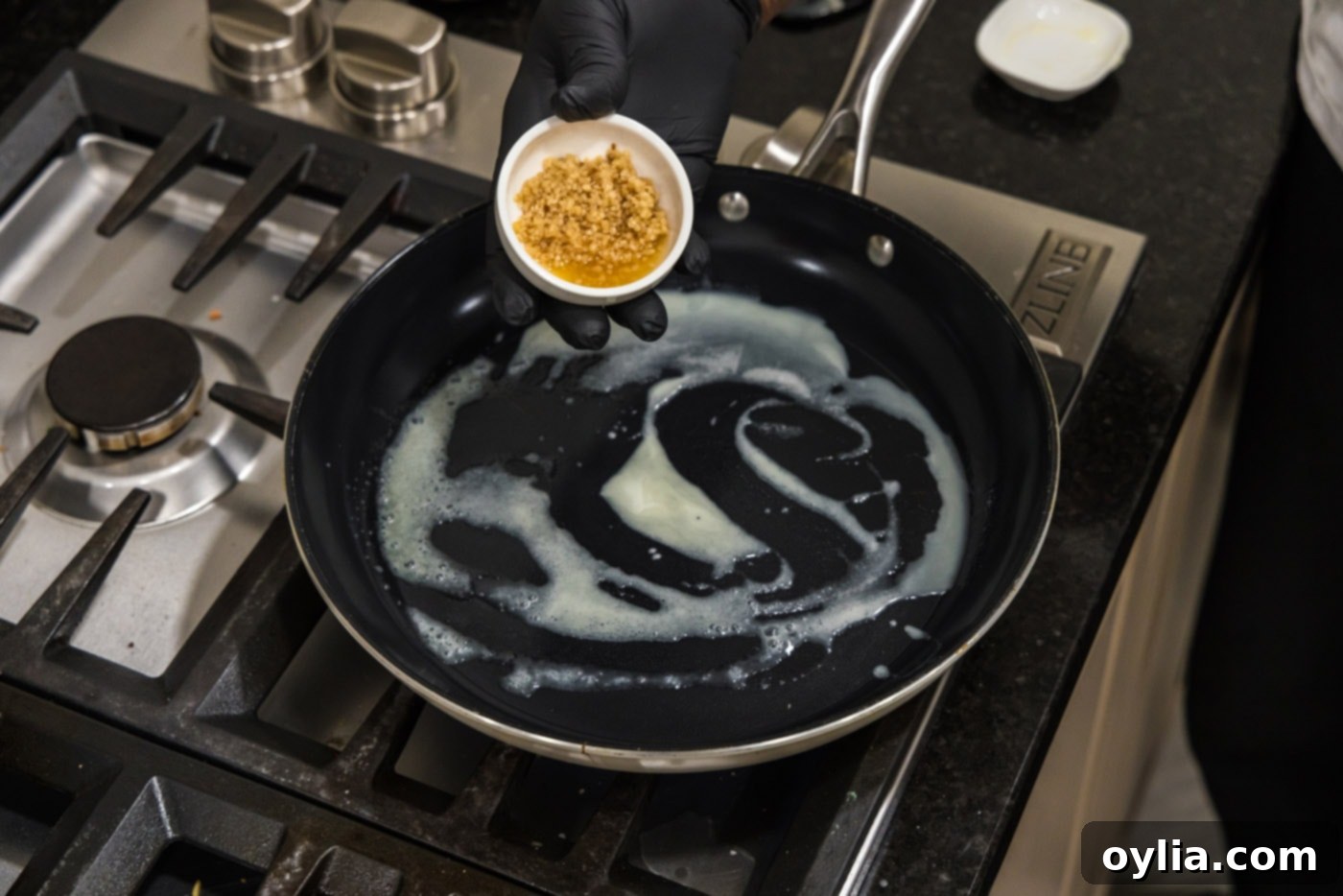 Adding minced garlic to a sizzling skillet with melted butter, creating a fragrant base for the hibachi shrimp.