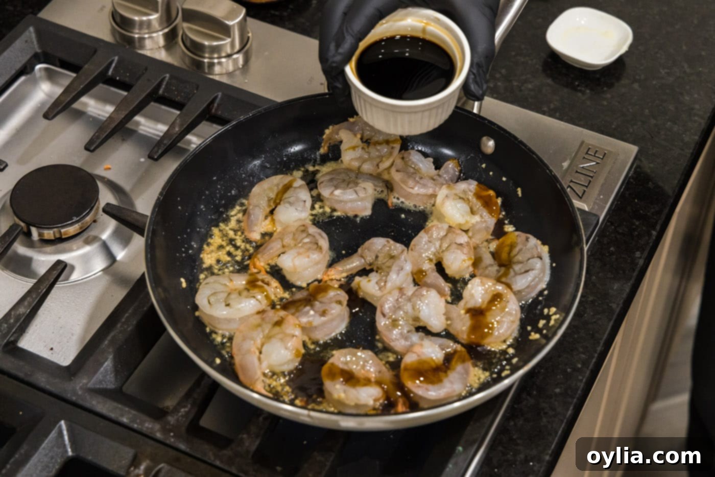 Adding soy sauce to the skillet with shrimp, sesame oil, and oyster sauce to create the flavorful hibachi glaze.