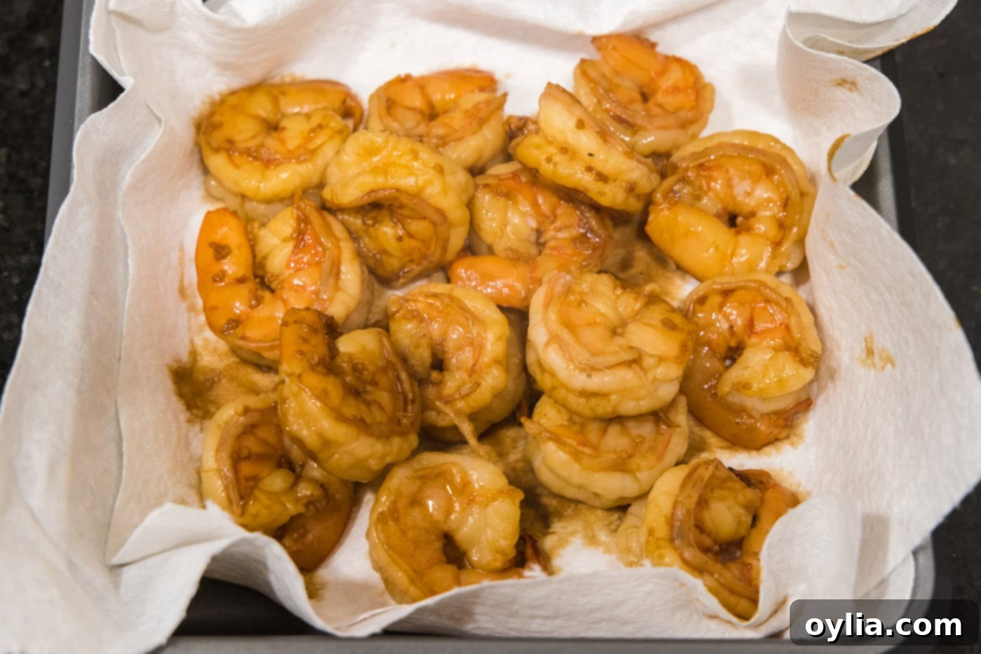 Freshly cooked hibachi shrimp draining on a paper towel-lined plate, ready to be served hot.