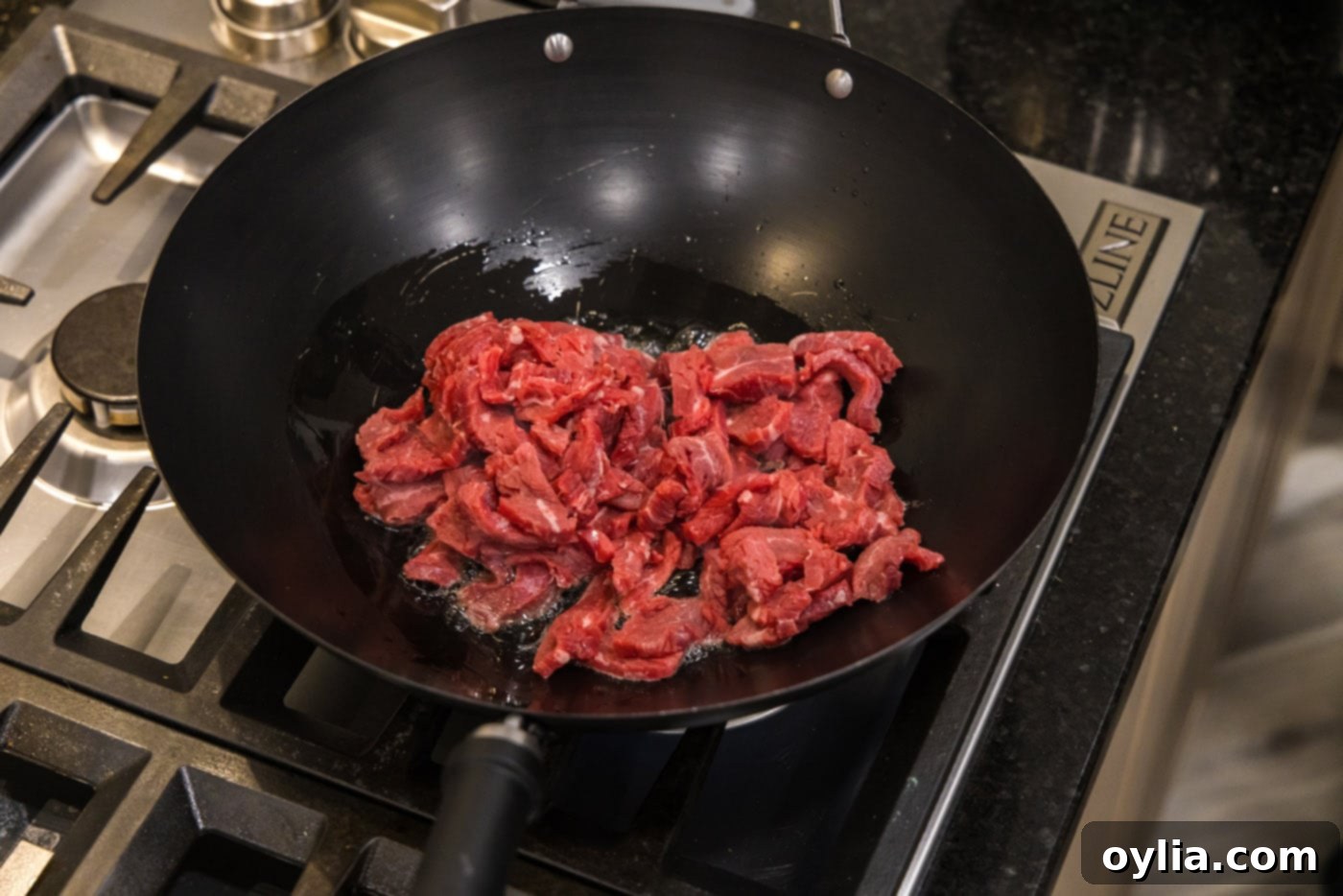 Flank steak strips sizzling in a hot wok with oil, browning beautifully