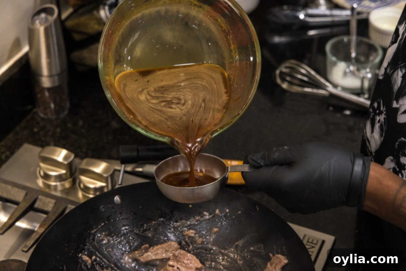 Pouring homemade teriyaki sauce into a measuring cup, preparing to add to the stir-fry