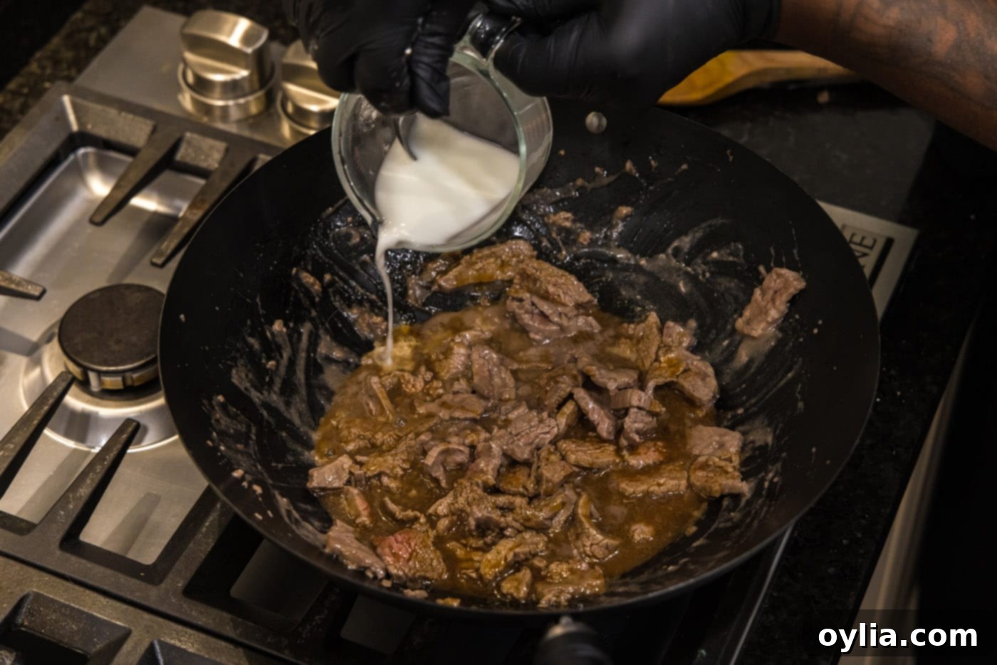 Adding cornstarch slurry to the skillet with beef strips and teriyaki sauce, for thickening