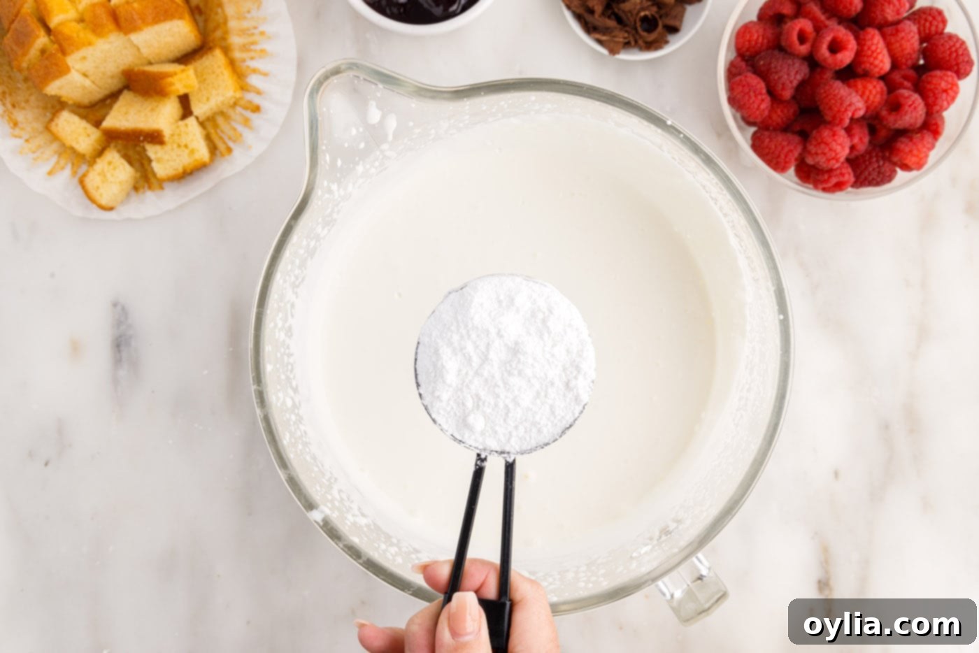 adding powdered sugar to heavy whipping cream in a bowl