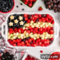 Red White & Blue Fruit Salad in a white serving dish surrounded by fruit