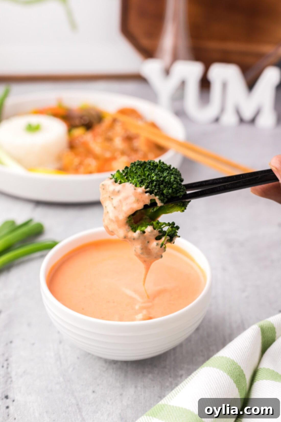 Instant Pot Broccoli florets being dipped into a bowl of creamy Yum Yum sauce.