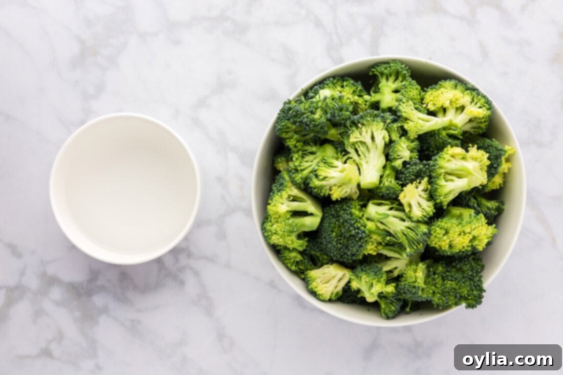 Ingredients laid out for Instant Pot Broccoli, including fresh broccoli florets and a measuring cup of water.