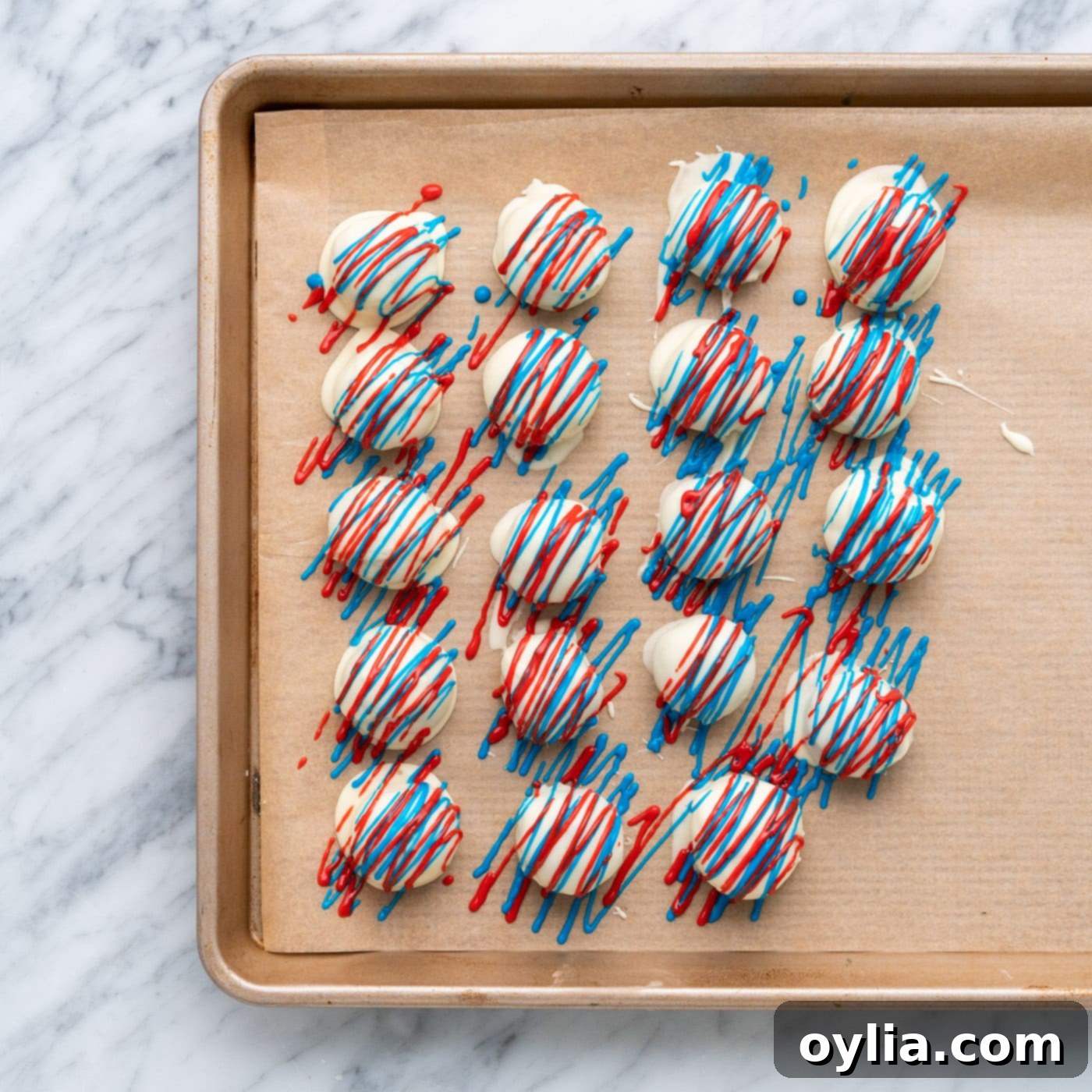 red and blue drizzled oreo truffles on a baking sheet