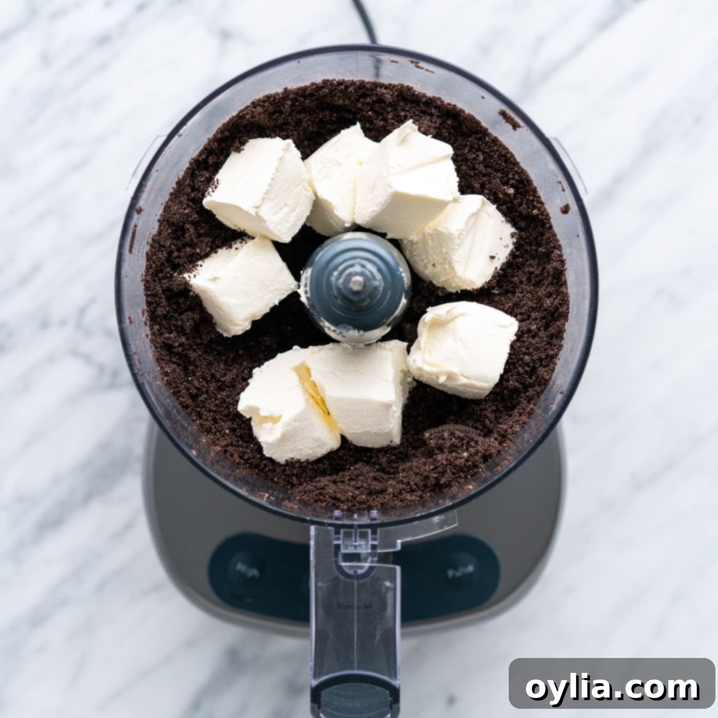 cubed cream cheese added to food processor with oreos