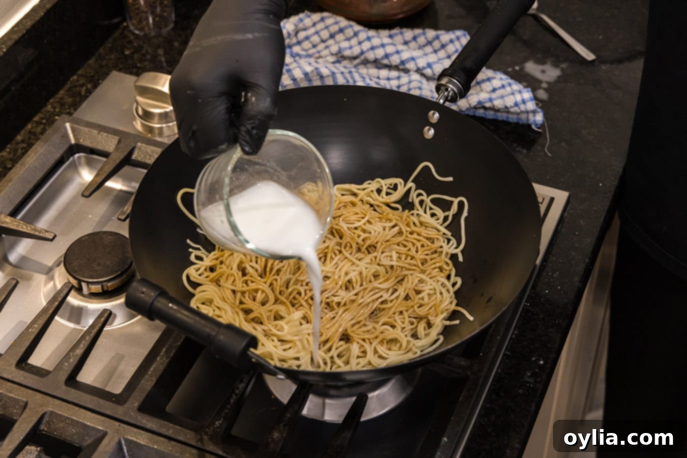 pouring a cornstarch slurry into teriyaki noodles to thicken the sauce