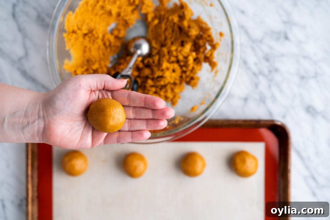 A perfectly rolled peanut butter cookie dough ball, ready for the baking sheet.