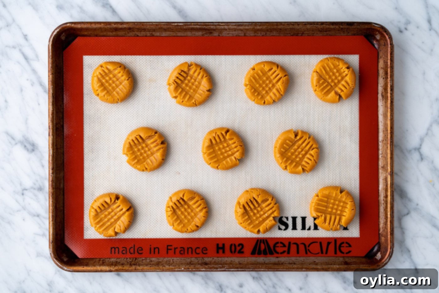 Peanut butter cookie dough arranged on a baking sheet, ready to go into the oven.