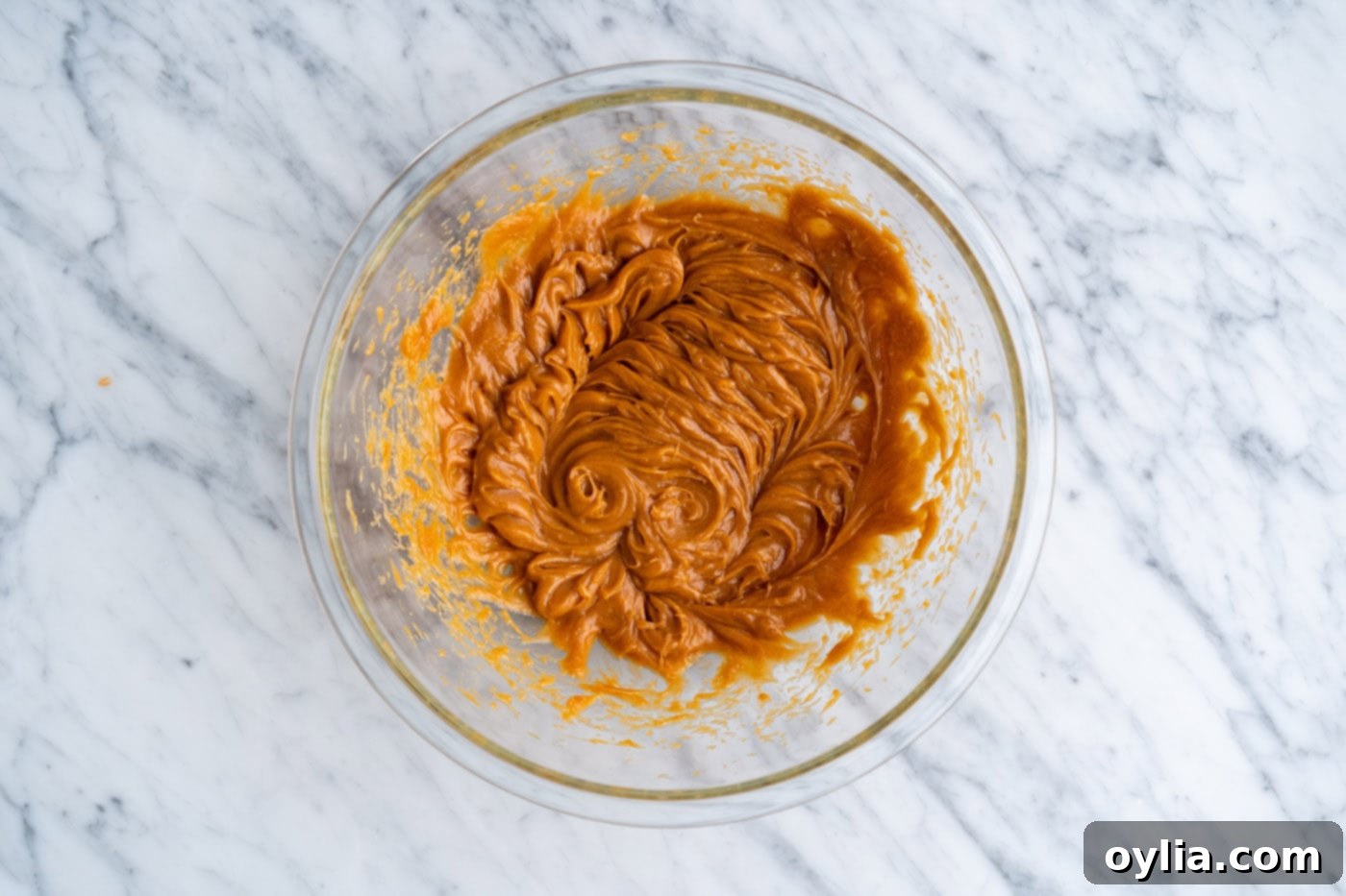 The eggs, oil, and peanut butter expertly mixed together in a bowl, creating a smooth, cohesive mixture.