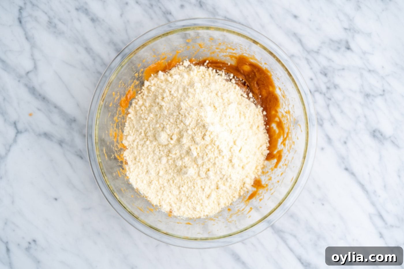 Yellow cake mix being added to the bowl with the mixed peanut butter, eggs, and oil.