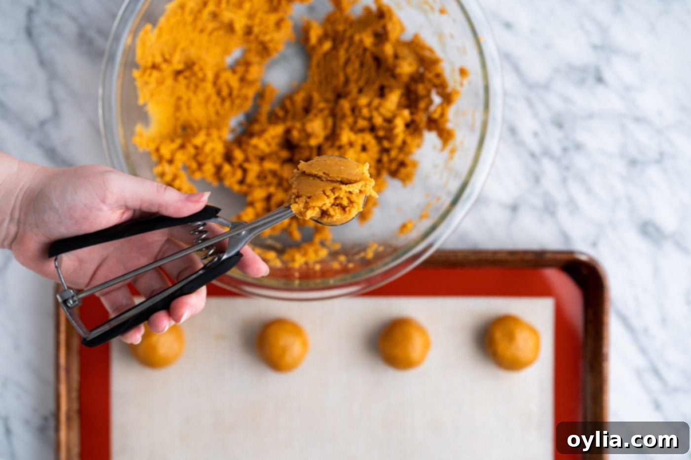 A cookie scoop gathering a portion of the peanut butter cookie dough.