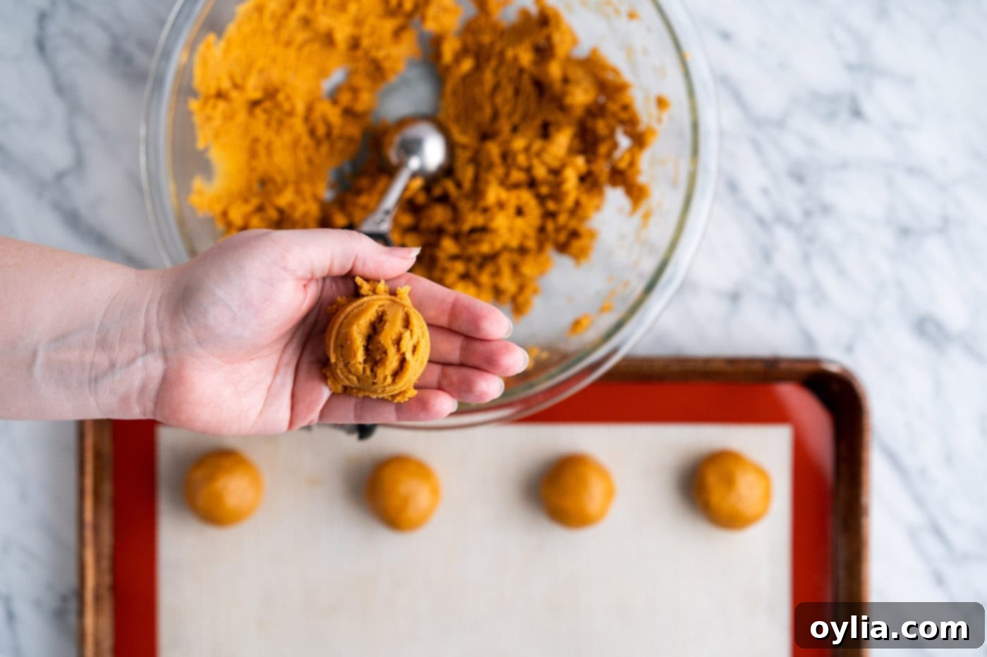 Hands rolling a portion of cookie dough into a smooth ball.