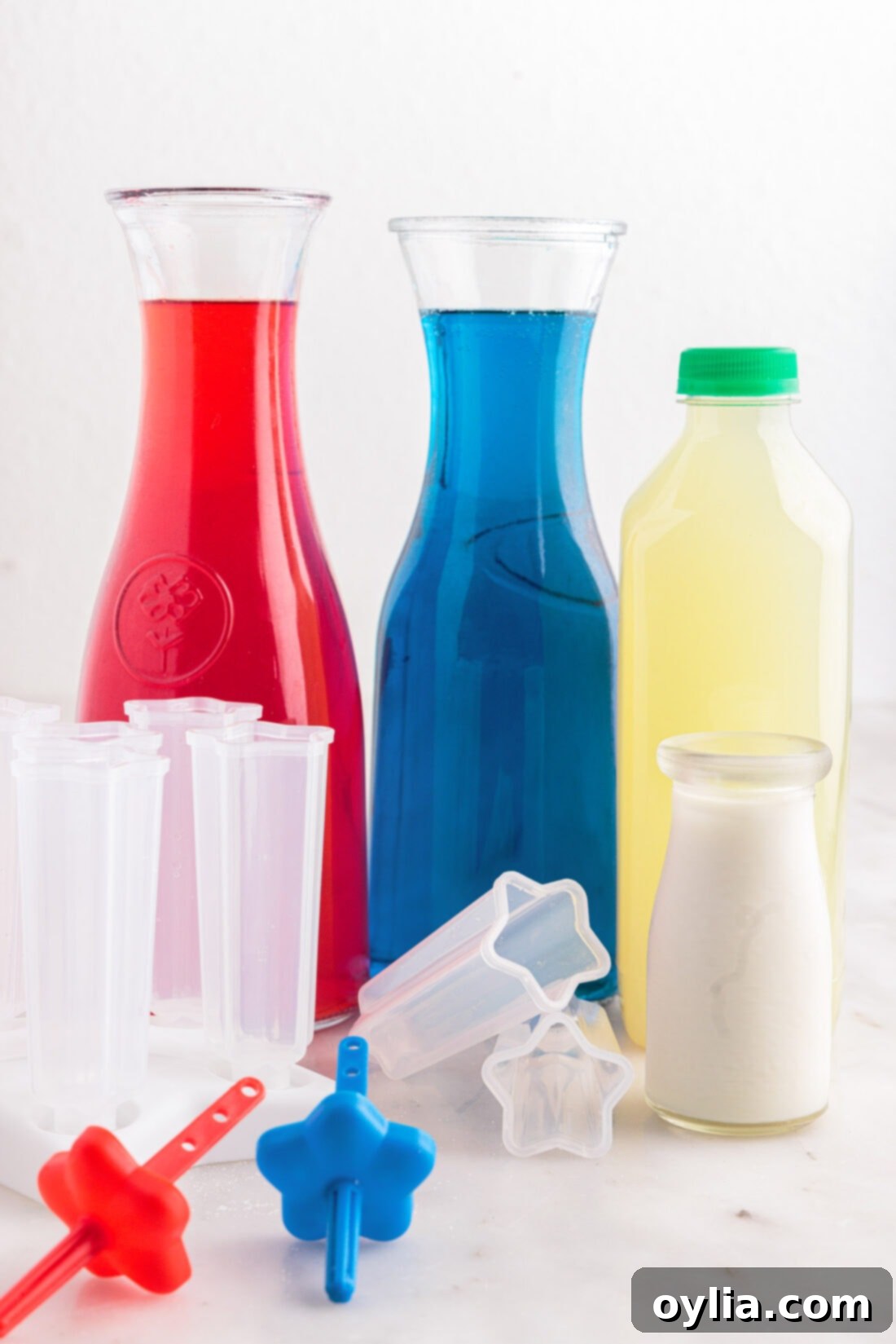 Stars and Stripes Rocket Pops 4 Ingredients for Patriotic Bomb Pop, including cherry and blue raspberry Kool-Aid packets, limeade, and heavy whipping cream, laid out on a clean surface.