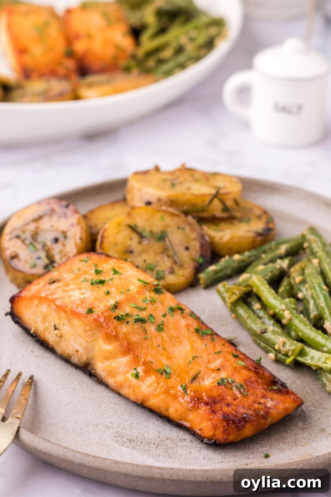 Brown Sugar Salmon on a plate with melting potatoes and garlic green beans
