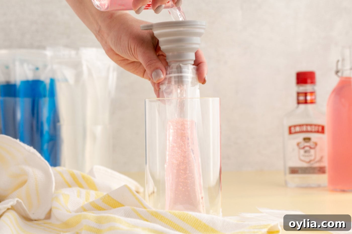 funneling vodka and juice into a popsicle sleeve