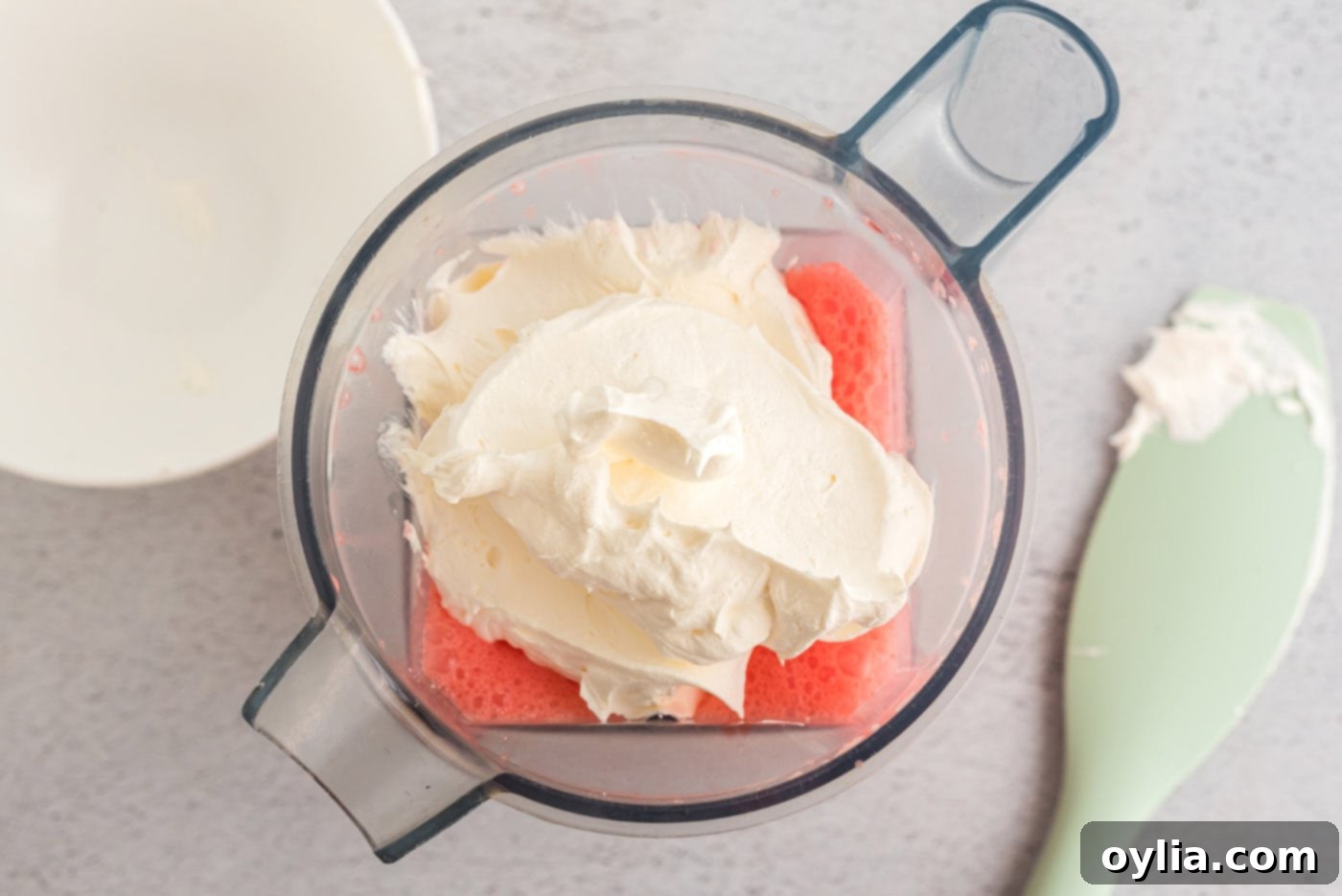 Adding a generous dollop of Cool Whip to the creamy Jell-O and cream cheese mixture in a blender before the final pulse.
