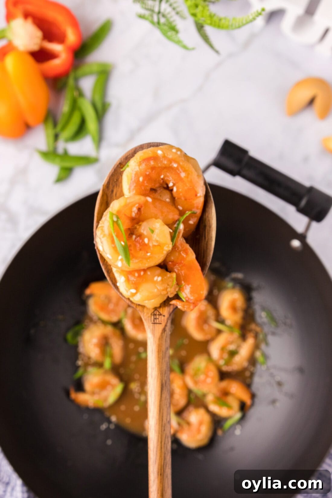 Spoonful of glossy Teriyaki Shrimp held above a steaming wok, ready to serve.
